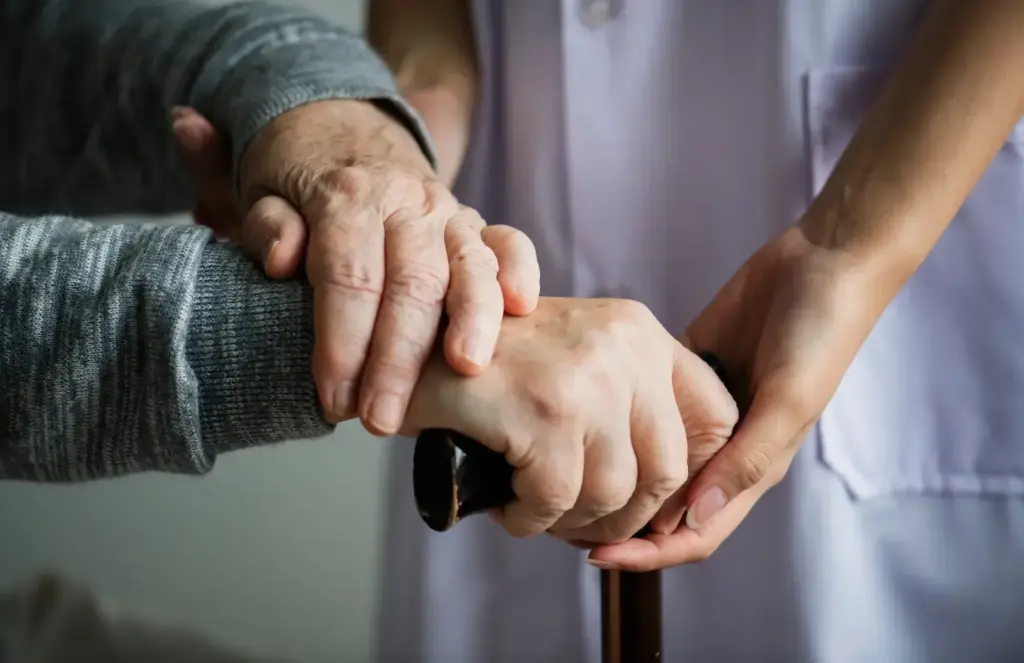 Detailaufnahme: Hände einer Seniorin am Gehstock, unterstützt von einer Pflegekraft – ambulante Pflege und sichere Alltagsbegleitung für mehr Stabilität und Selbstständigkeit zu Hause