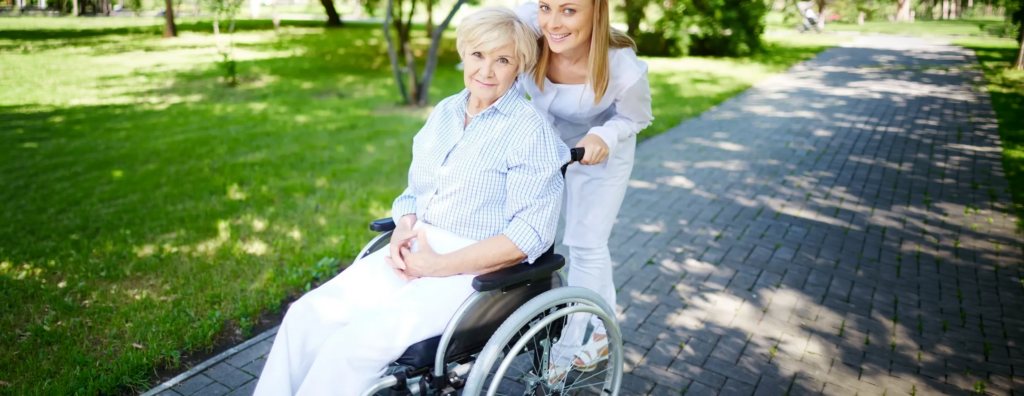 Pflegekraft schiebt Seniorin im Rollstuhl durch einen Park – ambulante Pflege und einfühlsame Begleitung für Mobilität und Lebensqualität im Alltag