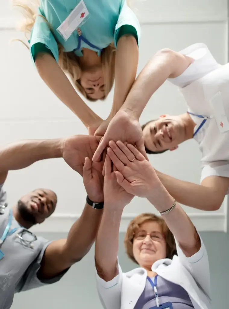 Pflege-Team hält Hände zusammen als Zeichen für Zusammenhalt – Pflegefachkräfte im ambulanten Pflegedienst arbeiten gemeinsam und unterstützen sich im Team